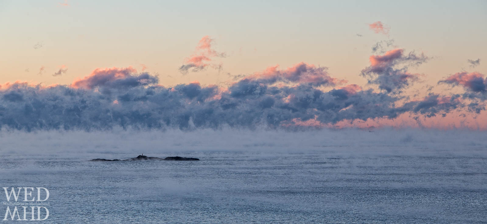 tom moore rock is surrounded by sea smoke