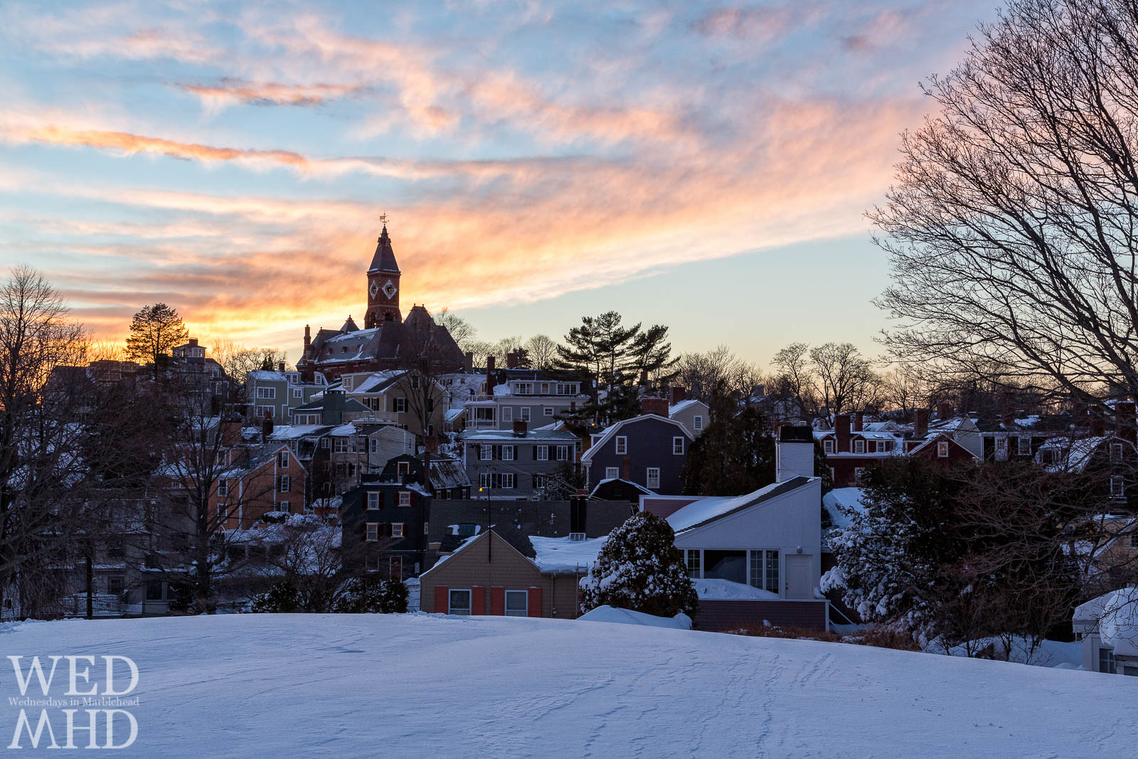 snow covered houses surround Abbot Hall in this view of sunset from Crocker Park