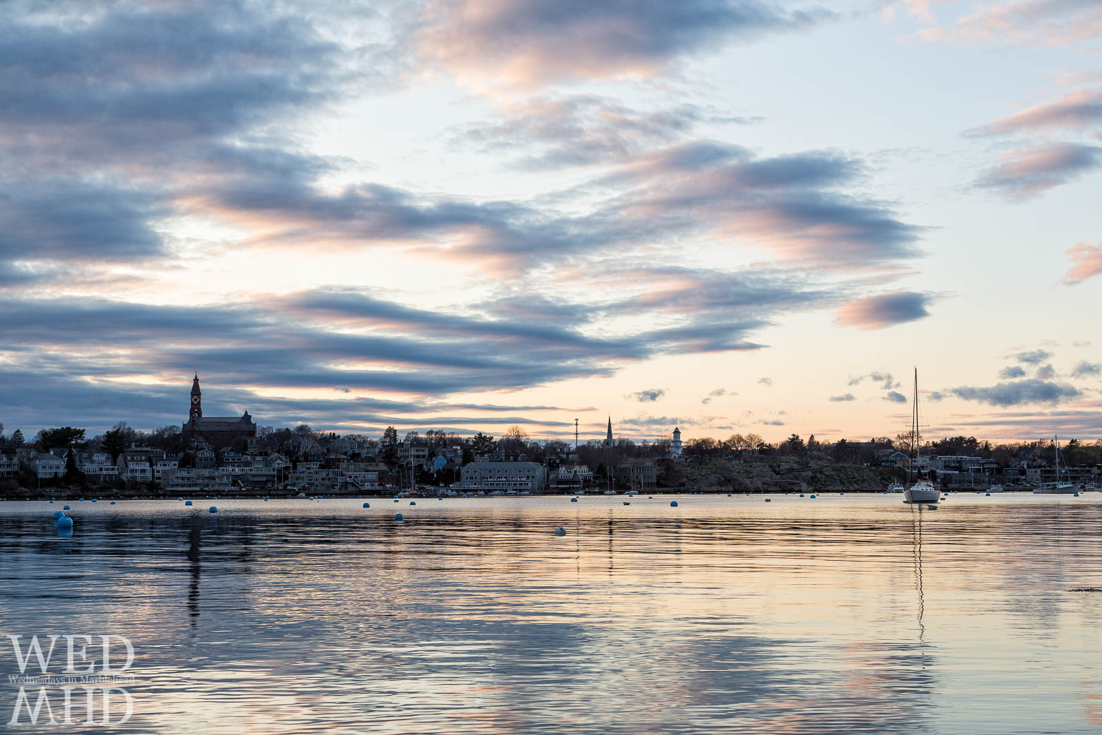 A single sailboat moored in Marblehead Harbor during sunset