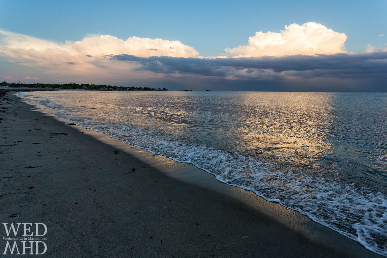 Clouds reflect the setting sun's light and form golden reflections in the ocean