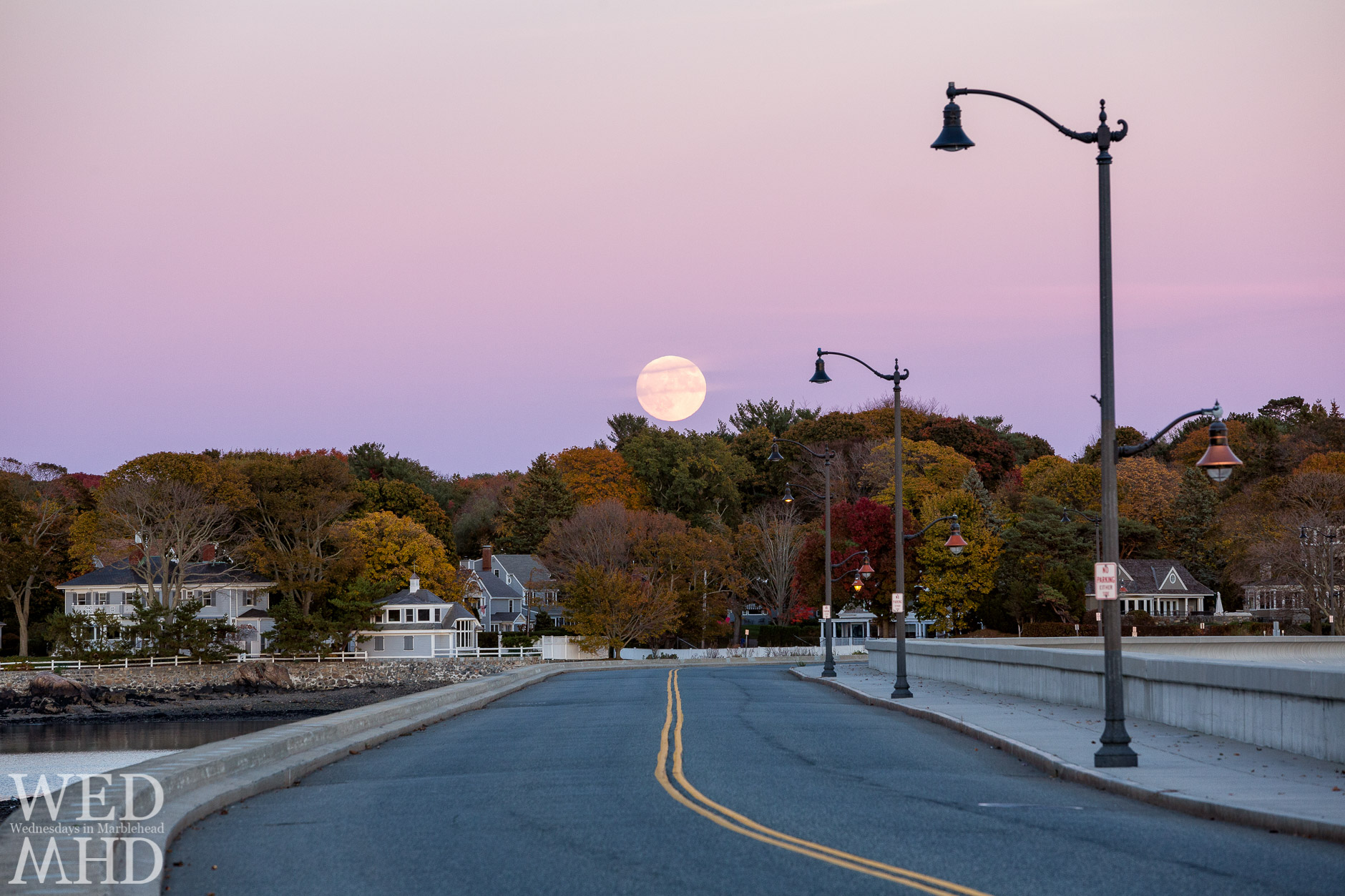 The full Hunter's moon rises over the causeway in Marblehead amidst peak foliage on the Neck