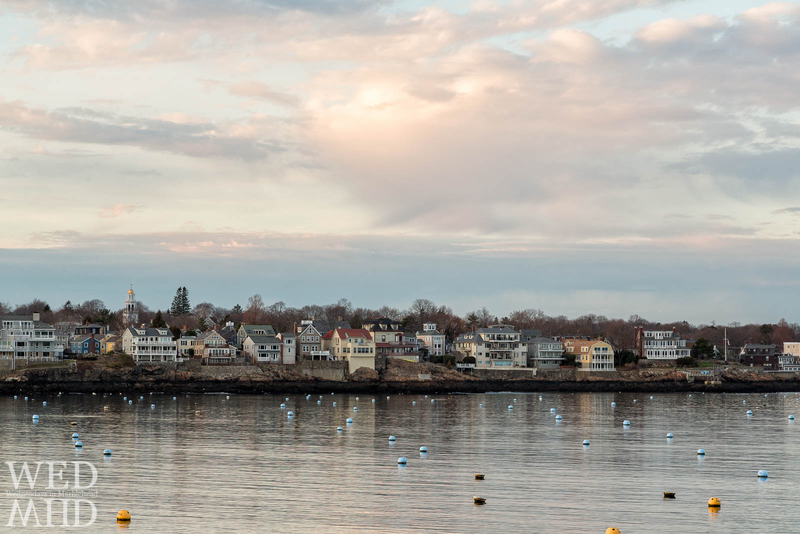 Soft light on an empty harbor with waterfront houses captured on Christmas Eve in Marblehead