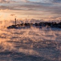 Tendrils of sea smoke dance across Marblehead Harbor at sunrise as arctic air causes water to form into steam