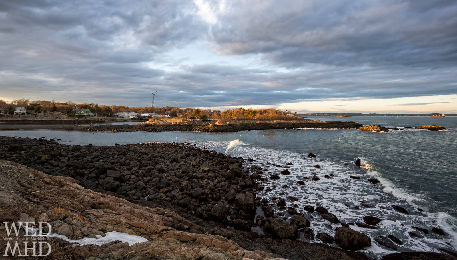 Waves roll in to little harbor at low tide  lit by the setting sun