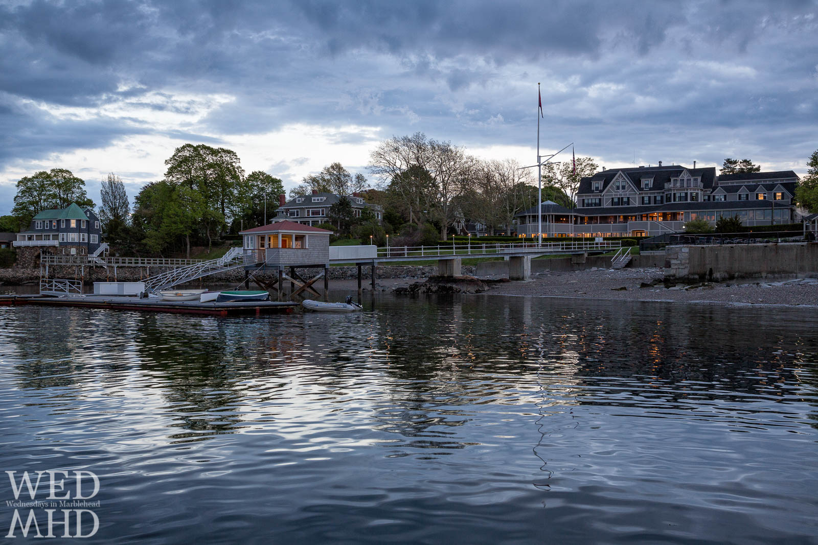 The lights of the Eastern Yacht Club are reflected in the still waters of Marblehead Harbor at sunset