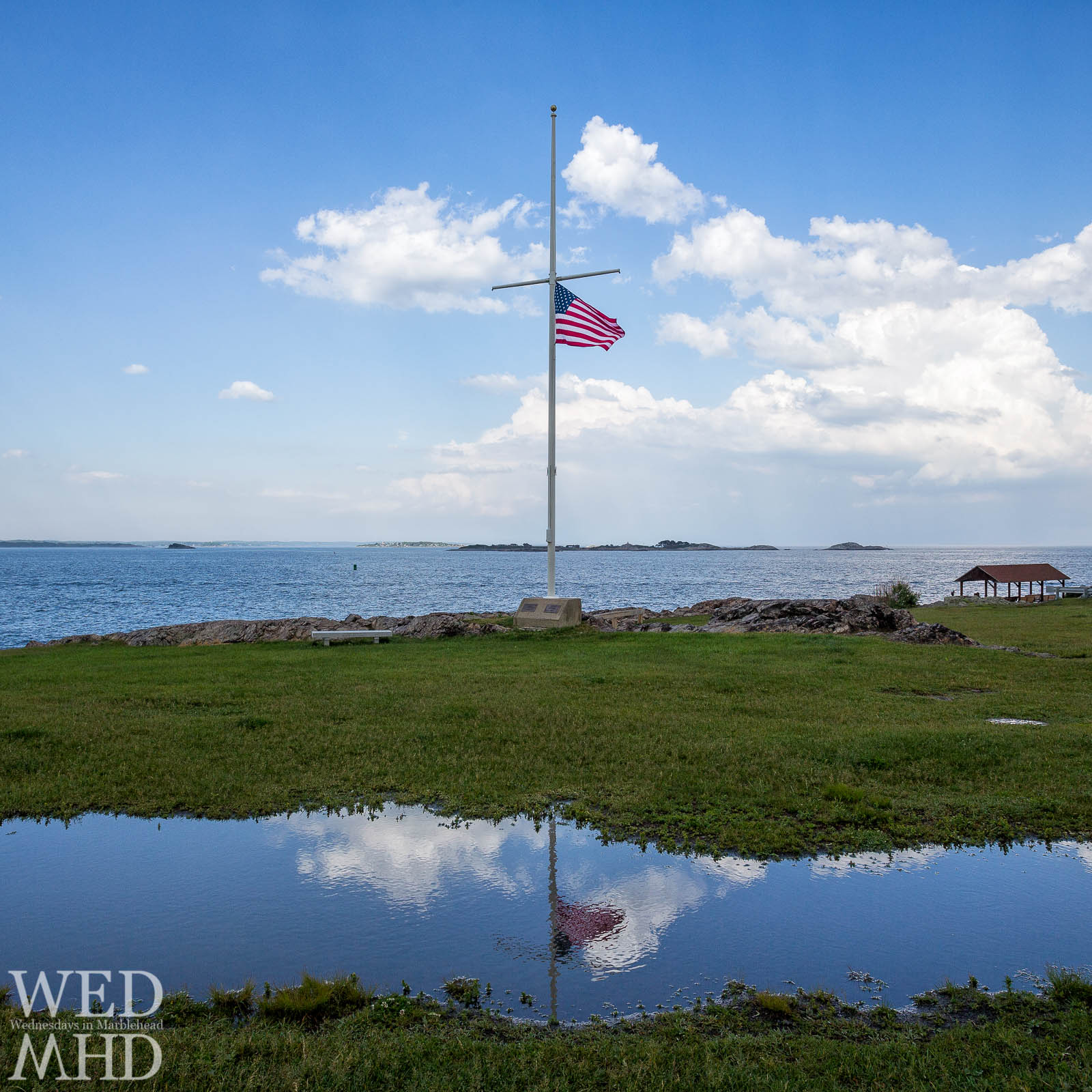 Old Glory at half mast reflecting in rainwater at Chandler Hovey Park