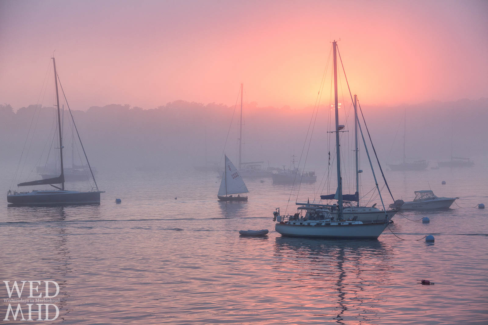 Purple fog fills the night sky and surrounds boats on their moorings in the still waters of Marblehead Harbor