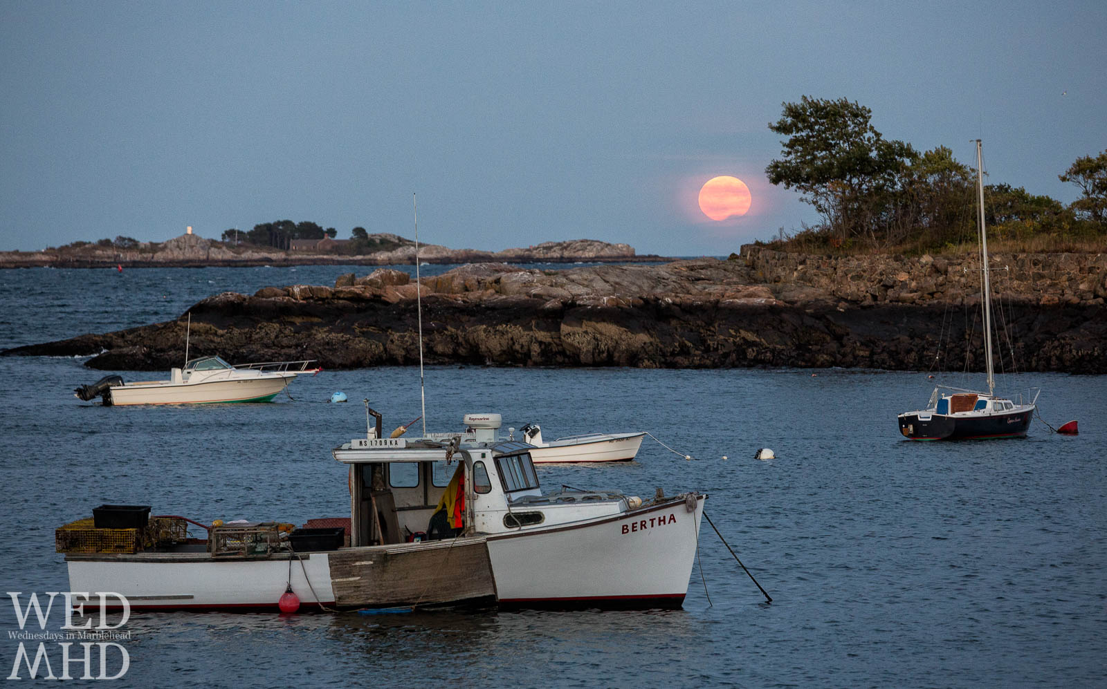 The working boat Bertha is moored in Little Harbor as the Harvest Moon rises over Marblehead
