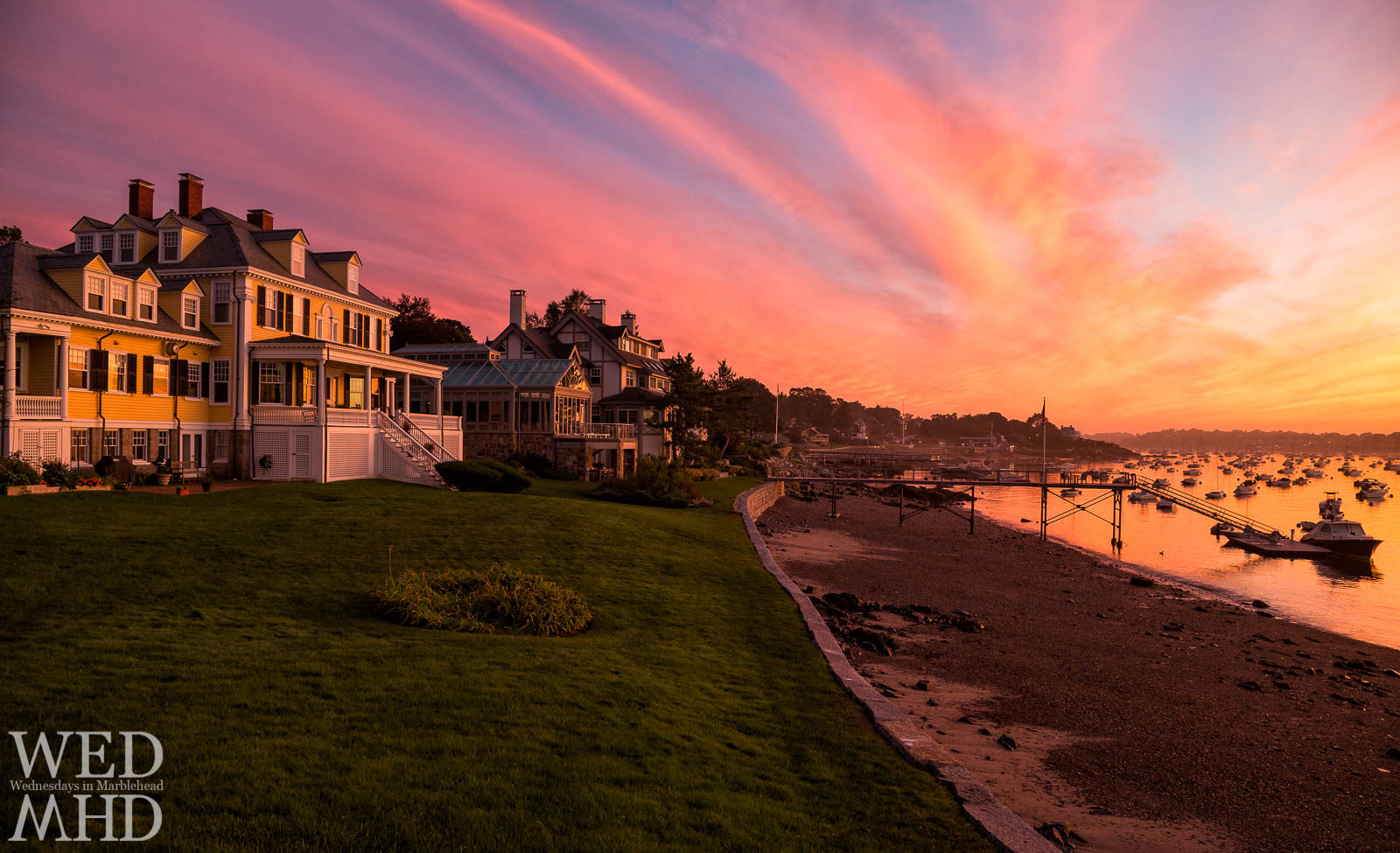 A beautiful sunset takes shape over Marblehead Harbor and reflects on these houses in a typical Summer night on the Neck