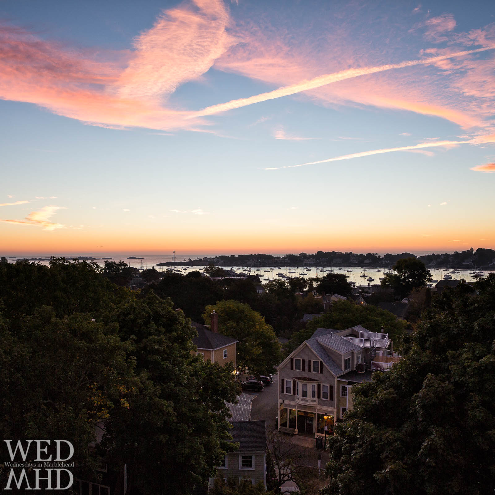 A rooftop view of the Muffin Shop at dawn with Marblehead harbor and its lighthouse in the distance