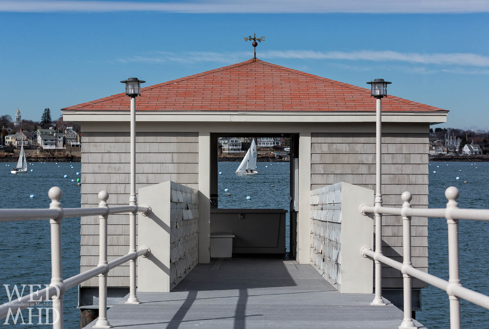 A sailboat taking part in frostbite sailing is framed by the pier house at the end of the Eastern Yacht Club pier