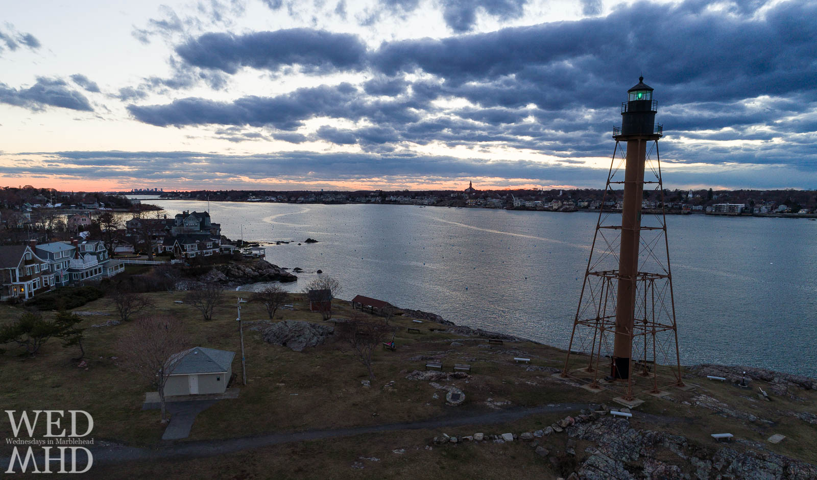 The green beacon of light at Chandler Hovey Park shines against the sunset of a March evening in Marblehead