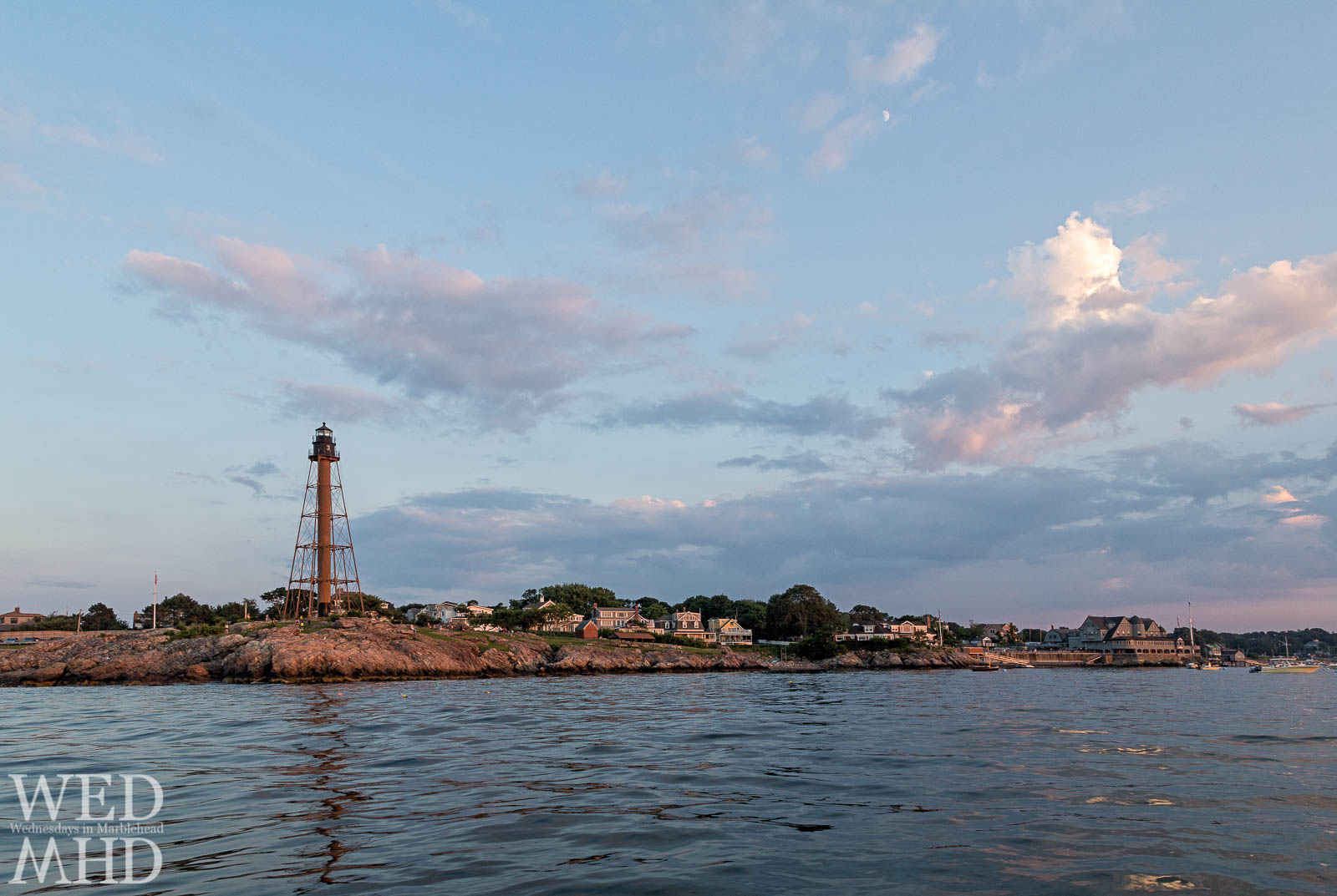 Marblehead Light is bathed in the last light of day as seen while heading into harbor by moonlight on a July evening
