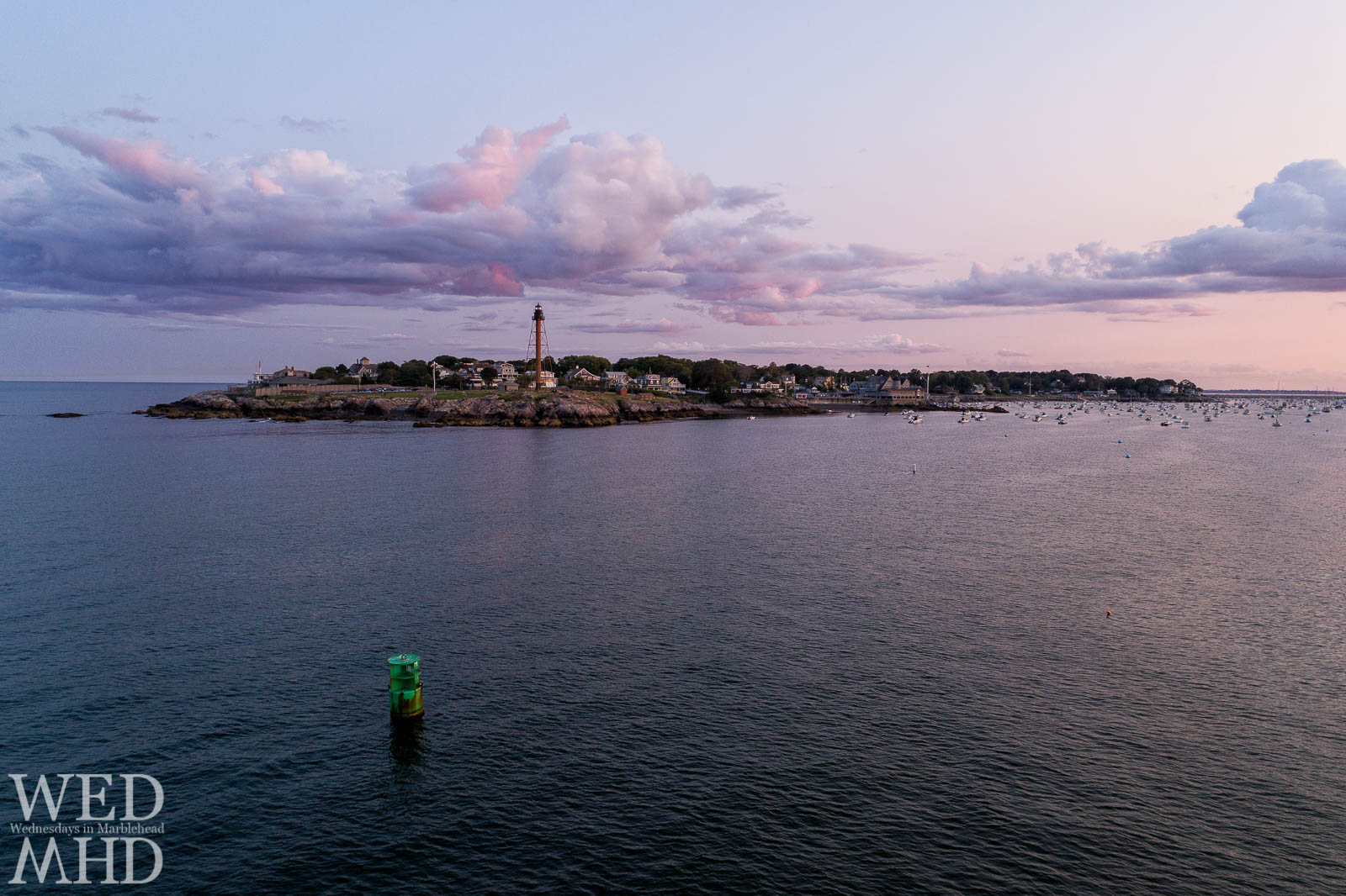 Clouds over Marblehead Neck reflect the pink hues of sunset as seen from the mouth of the harbor over the 1MH buoy