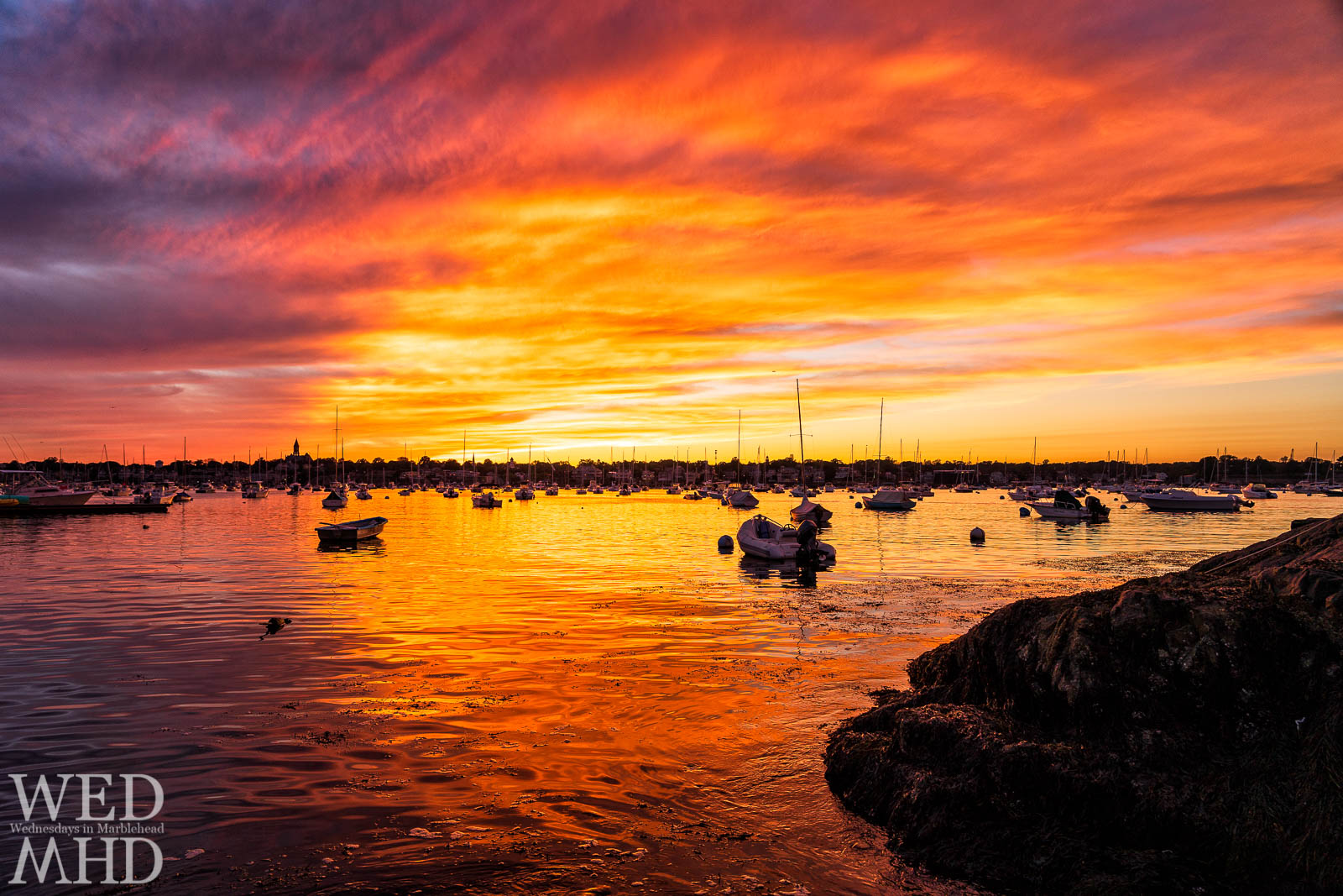 Sunset erupts in an explosion of light over Marblehead Harbor and paints the water in an orange glow