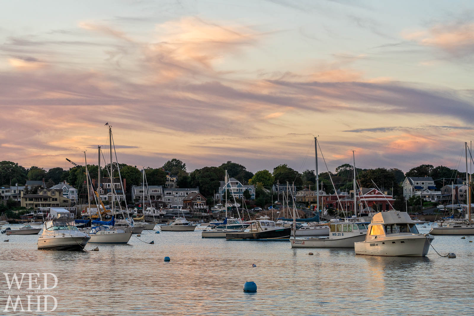 Sunset is reflected in the windows of a boat moored mid-harbor as the moorings begin to empty with the calendar turning to October