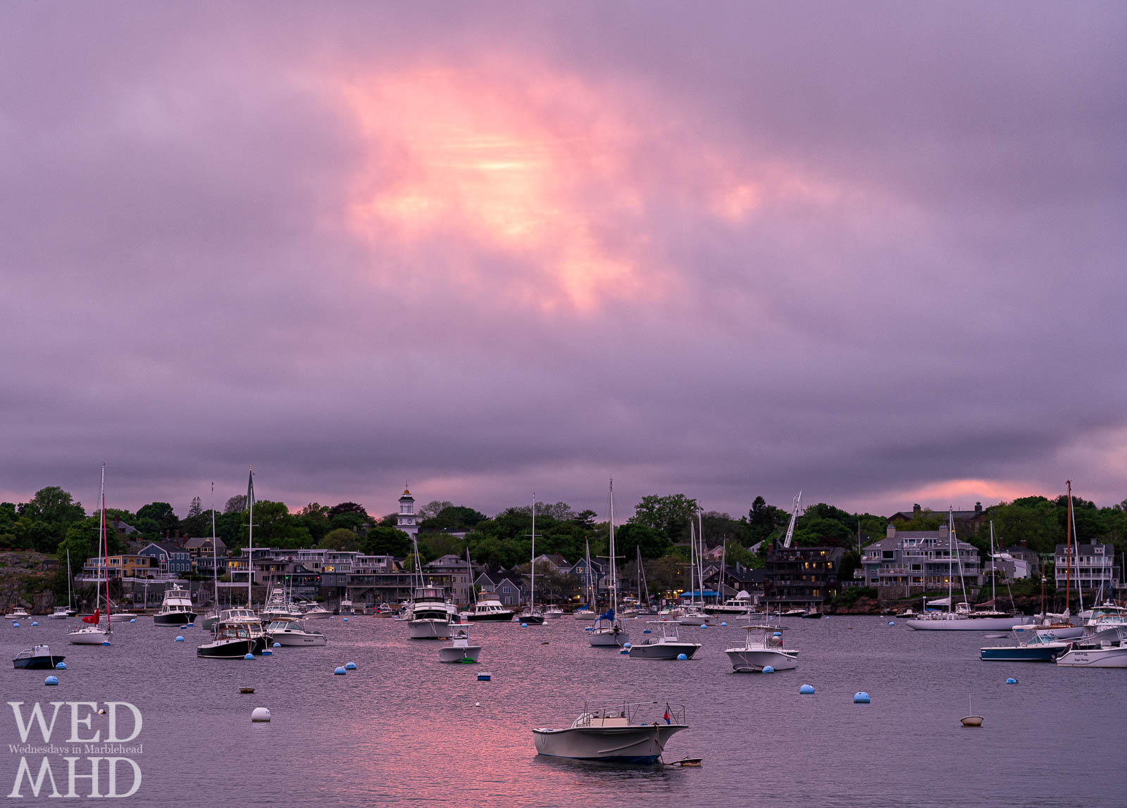 A boat is moored in the glow of an unusual sunset following a day of rain and grey clouds in Marblehead
