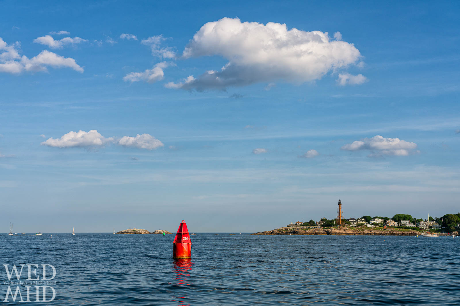A red channel marker labeled 3MH is captured marking the harbor entrance into Marblehead with the lighthouse on Chandler Hovey Park in the background