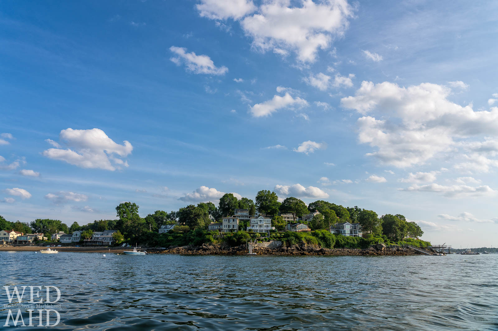 View of houses along Naugus Head in Marblehead from the water of Salem harbor on a warm summer evening