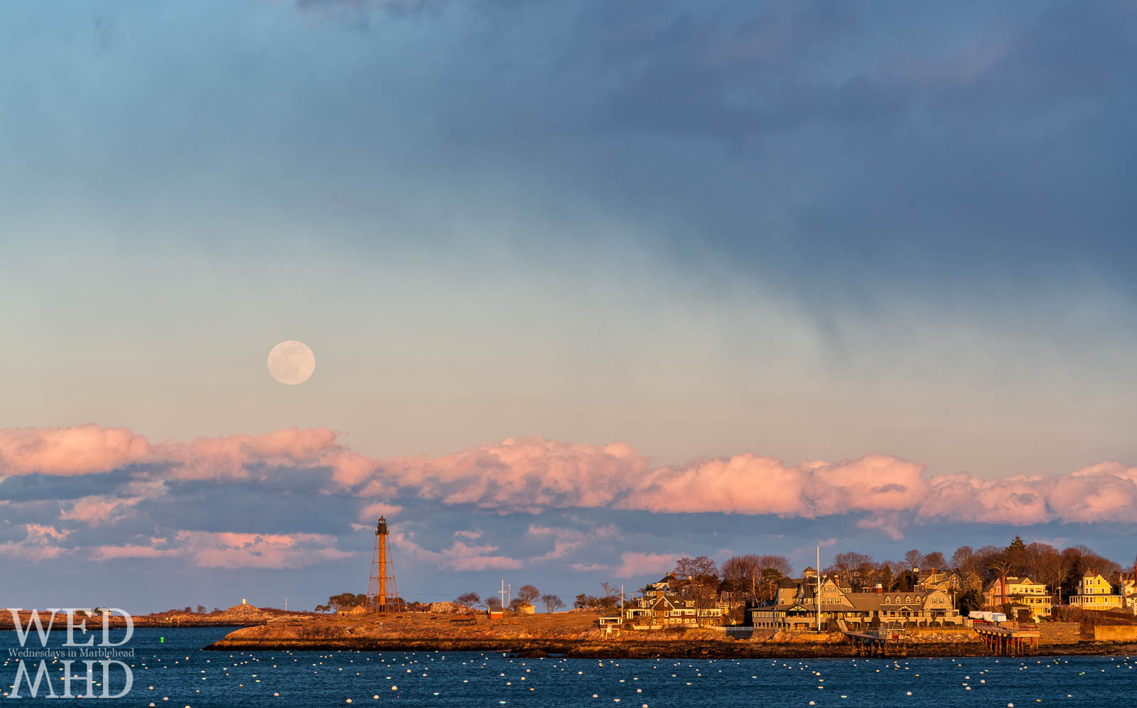 The full Snow moon rises over Marblehead Light and Childrens Island during a winter without snow