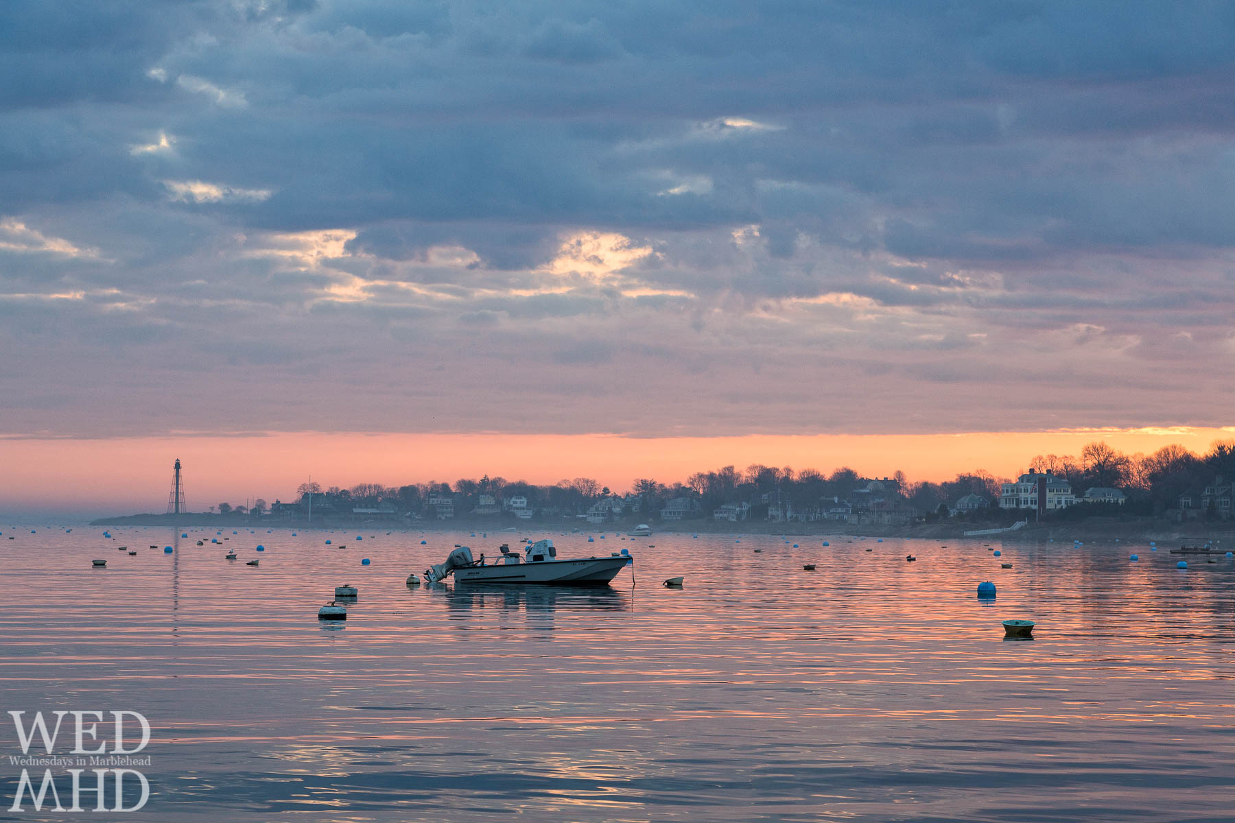 A lone Whaler moored in Marblehead Harbor and captured on a spring dawn with fog hovering over the water