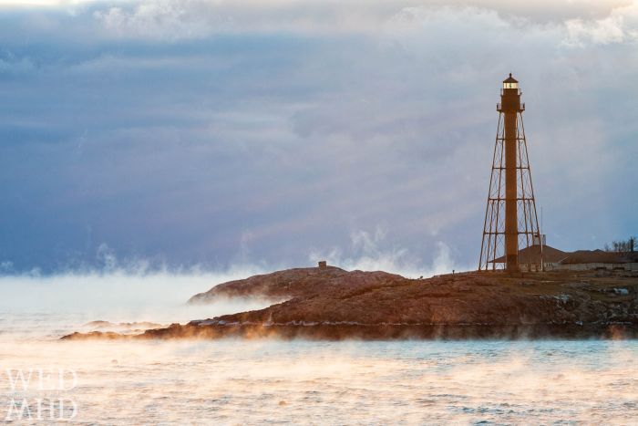 Sea smoke rises from the warm ocean waters and into the frigid air encircling Marblehead Light at dawn