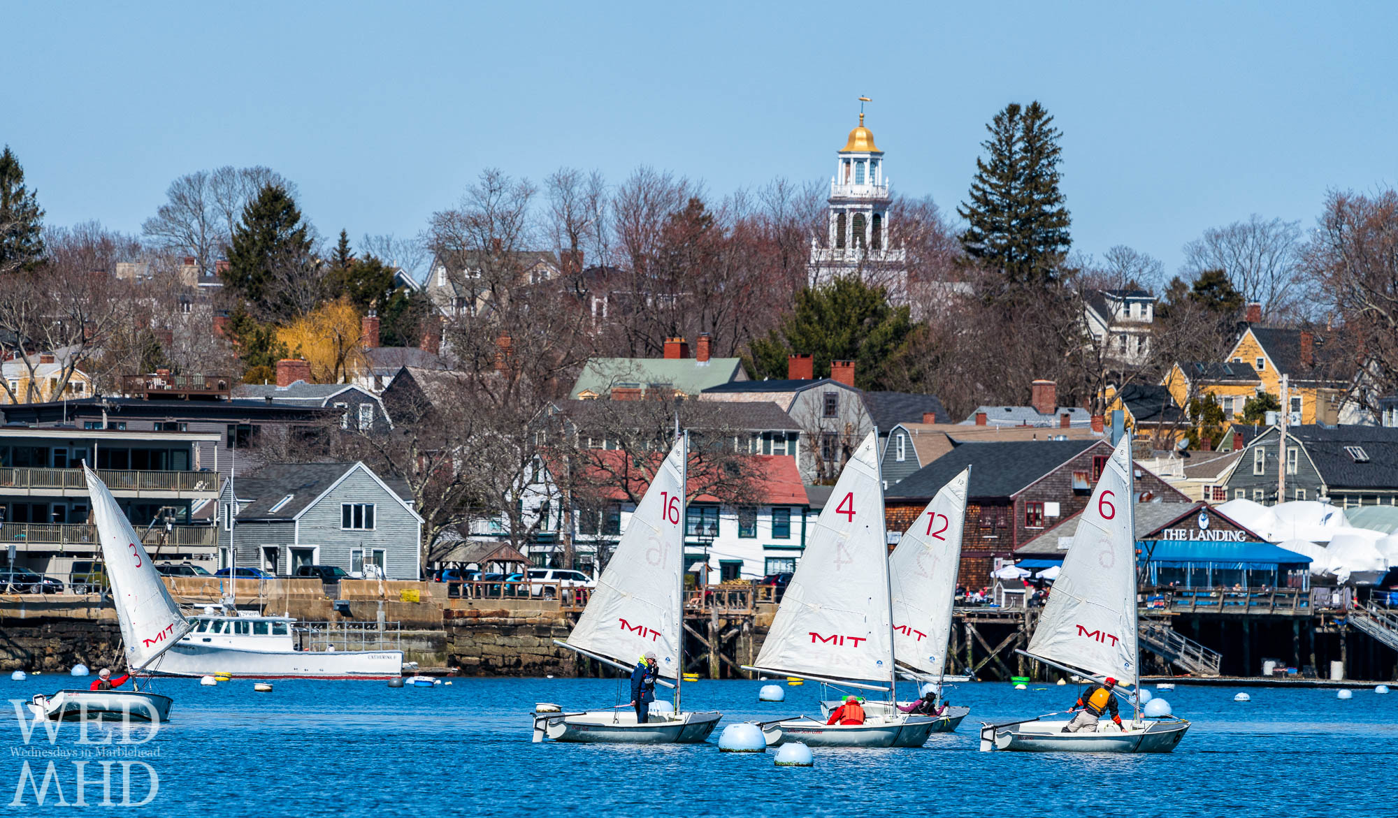 A group is seen passing by The Landing restaurant and Old North Church during the Marblehead Tech Dinghy Association inner harbor race
