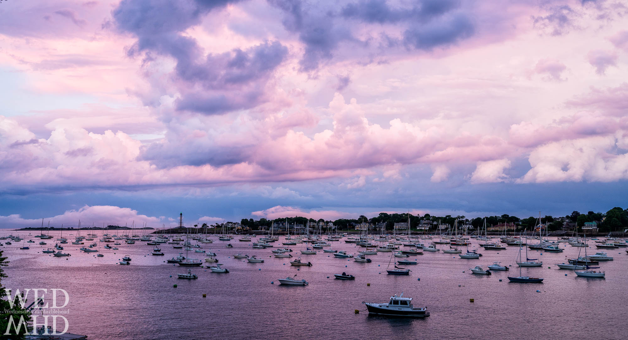 The last light of a great sunset creates a purple afterglow over Marblehead Harbor with the lighthouse's green beacon shining through