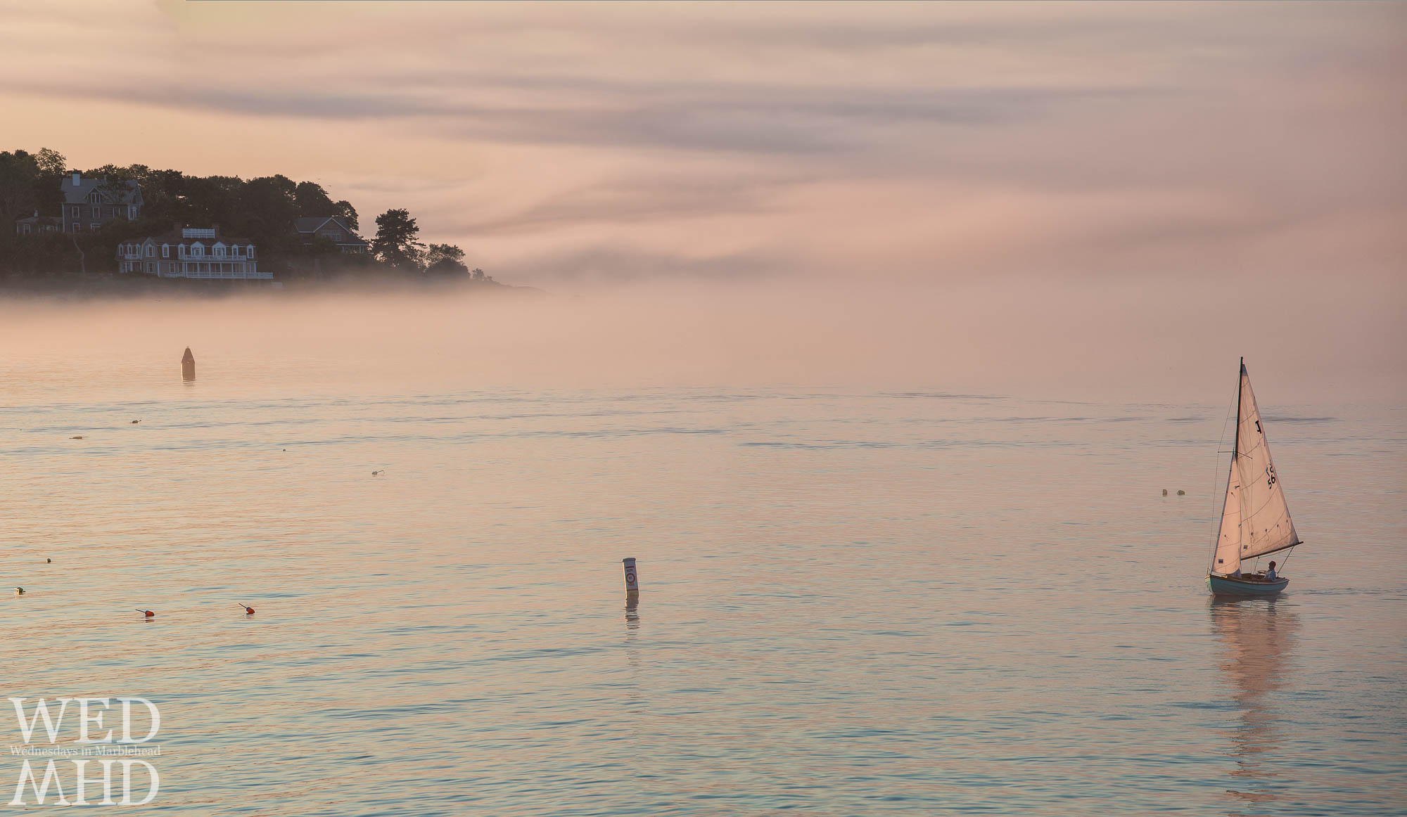 A lone town class boat heads back on a beautiful foggy evening in Marblehead harbor