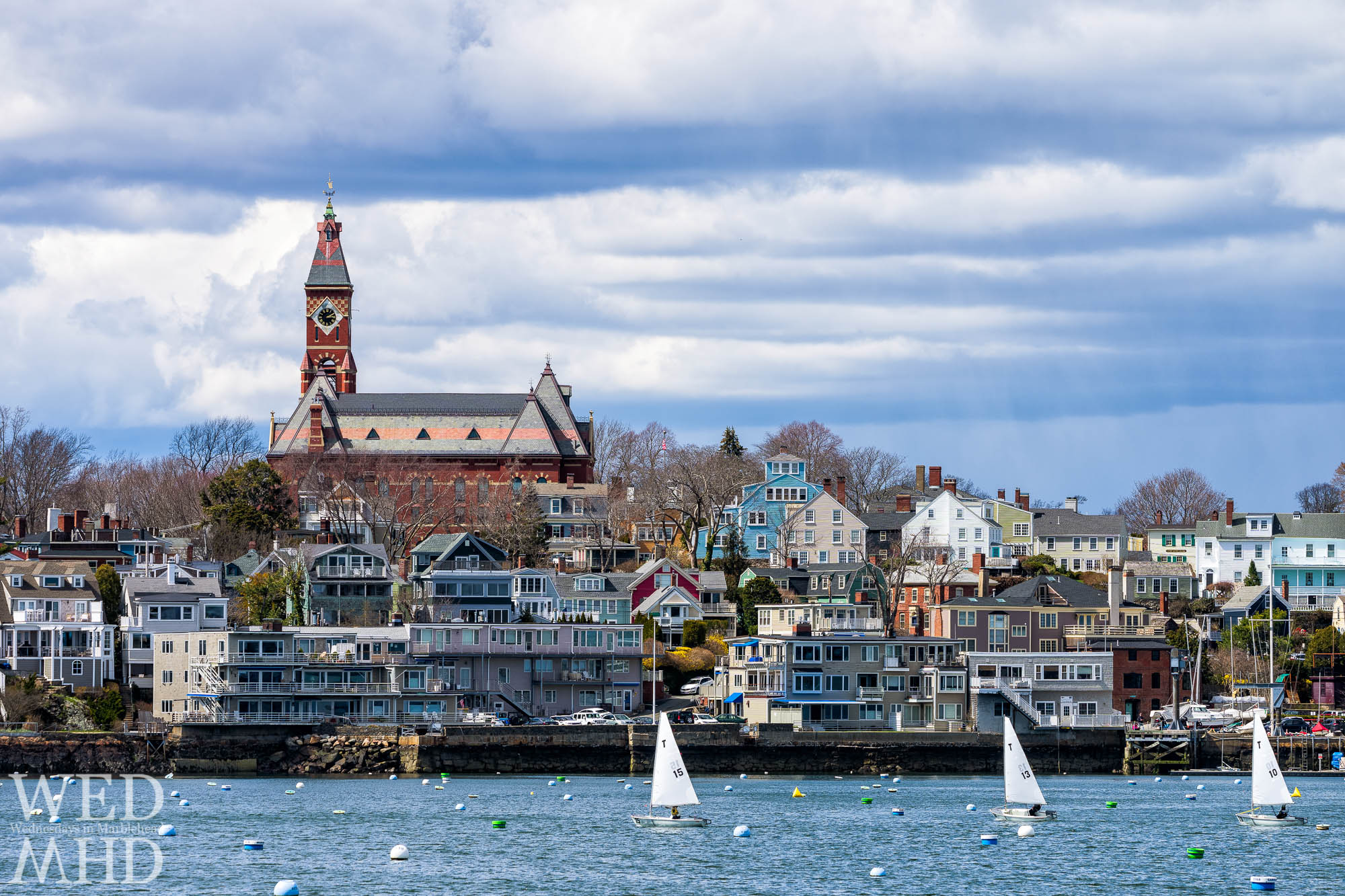 The last day of tech dinghy frostbite racing on a warm day with spring in the air and boats crossing in front of Abbot Hall